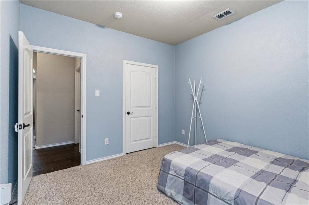 1713 Falling Star Drive, Fort Worth, TX 76052 Carpeted flooring, light blue wall paint, white trim, white paneled door, and dark hardware