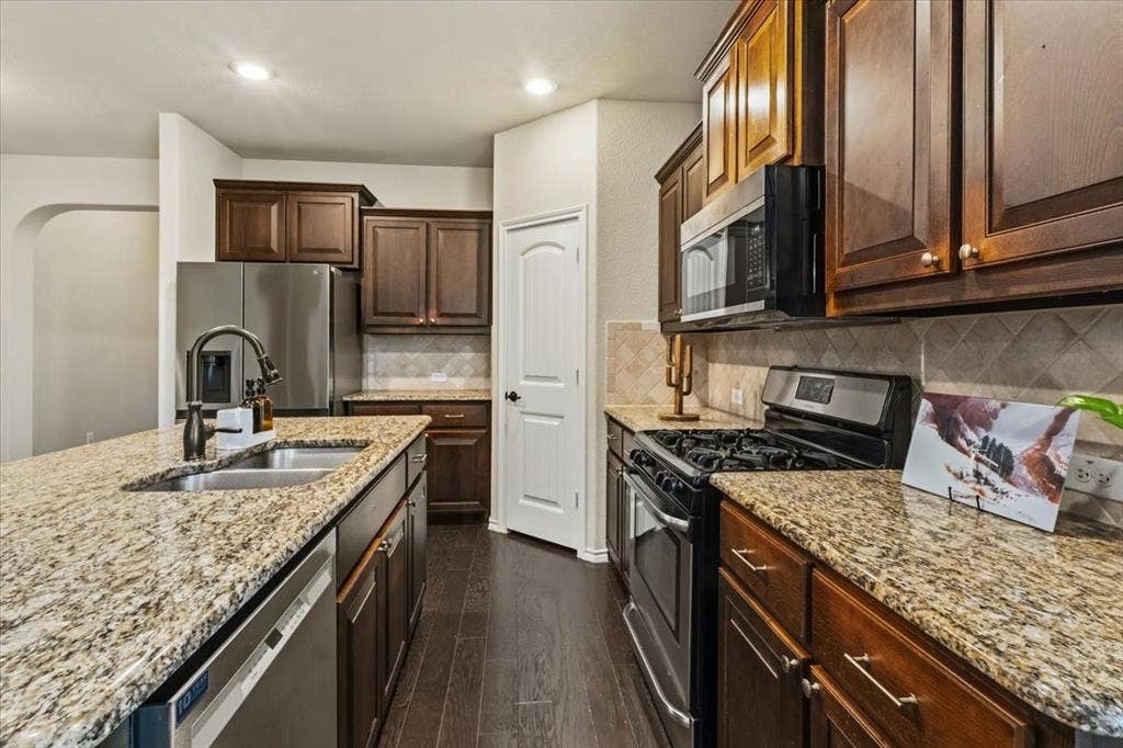 1713 Falling Star Drive, Fort Worth, TX 76052 Kitchen featuring granite countertops, wood-finish flooring, stainless steel appliances, dark wood cabinetry, and recessed lighting