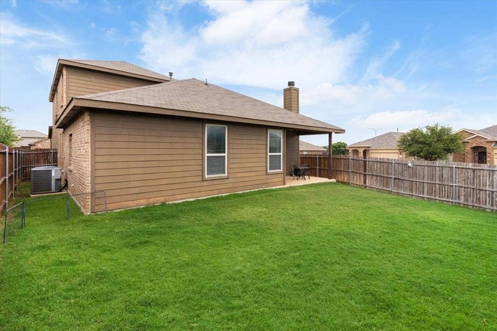 1713 Falling Star Drive, Fort Worth, TX 76052 Expansive grass lawn with wood privacy fencing, a covered concrete patio, and a visible HVAC unit