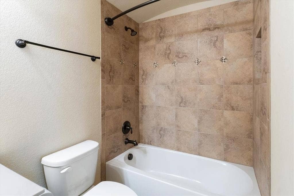 1713 Falling Star Drive, Fort Worth, TX 76052 Tub and shower combination featuring tile surround, decorative accent tiles, and oil-rubbed bronze fixtures