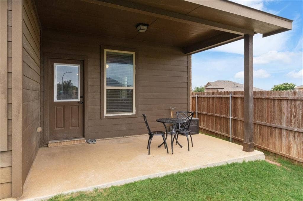 1713 Falling Star Drive, Fort Worth, TX 76052 Covered concrete patio featuring an exterior door, single window, and slatted wood fencing