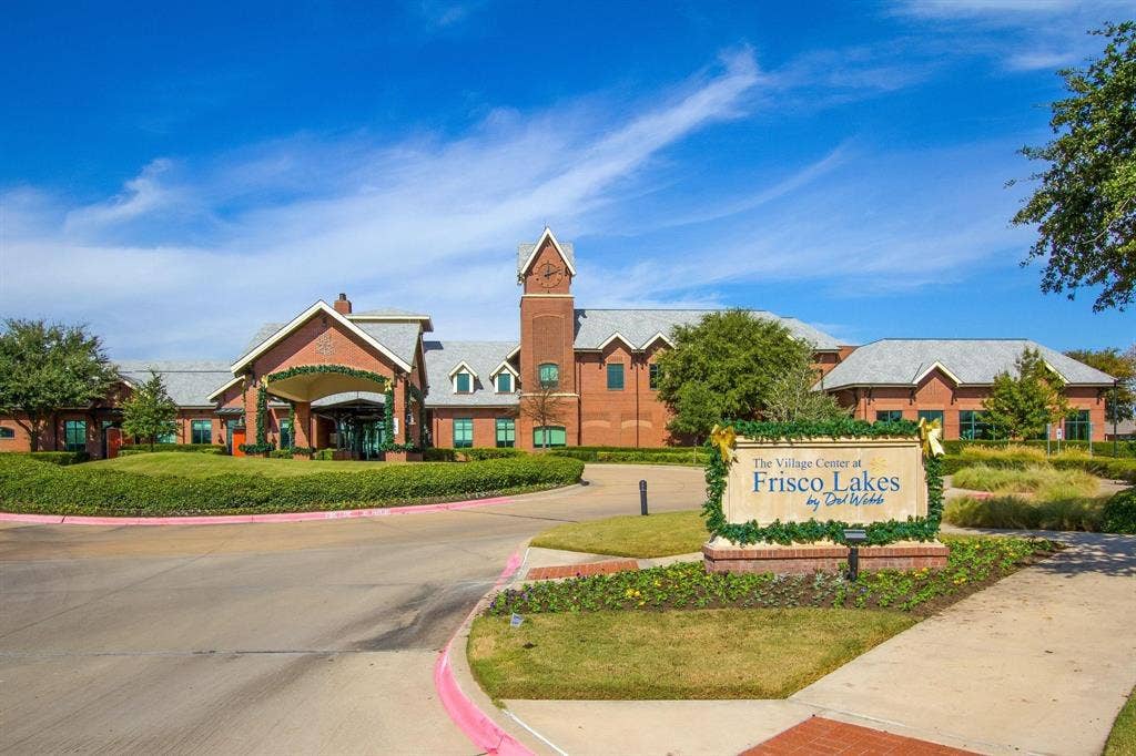 Red brick exterior, prominent clock tower, gabled entry, grey shingle roofing, and established landscaping