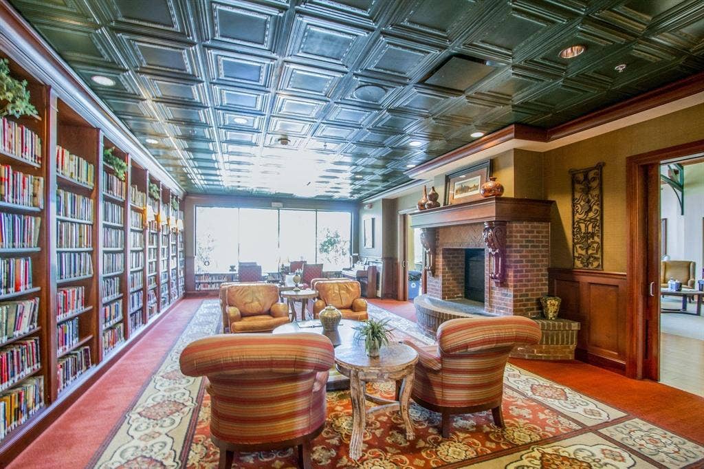 Recessed lighting, pressed tin ceiling, built-in shelving, brick fireplace, and wood paneling