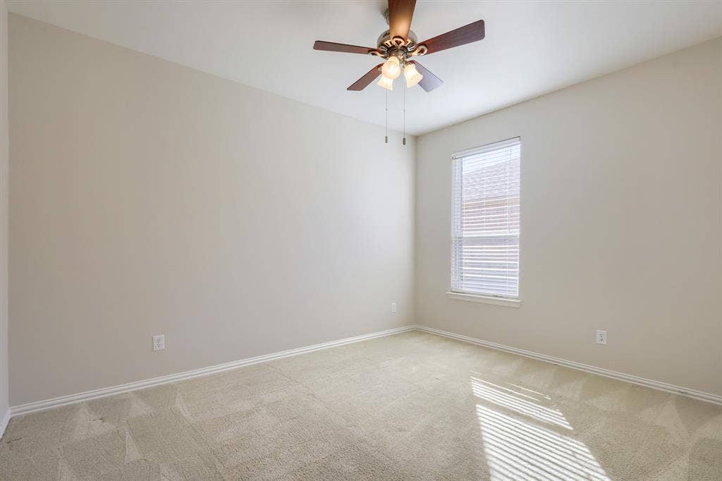Neutral-toned walls, light-toned carpet flooring, window with horizontal blinds, and a ceiling fan with integrated lighting