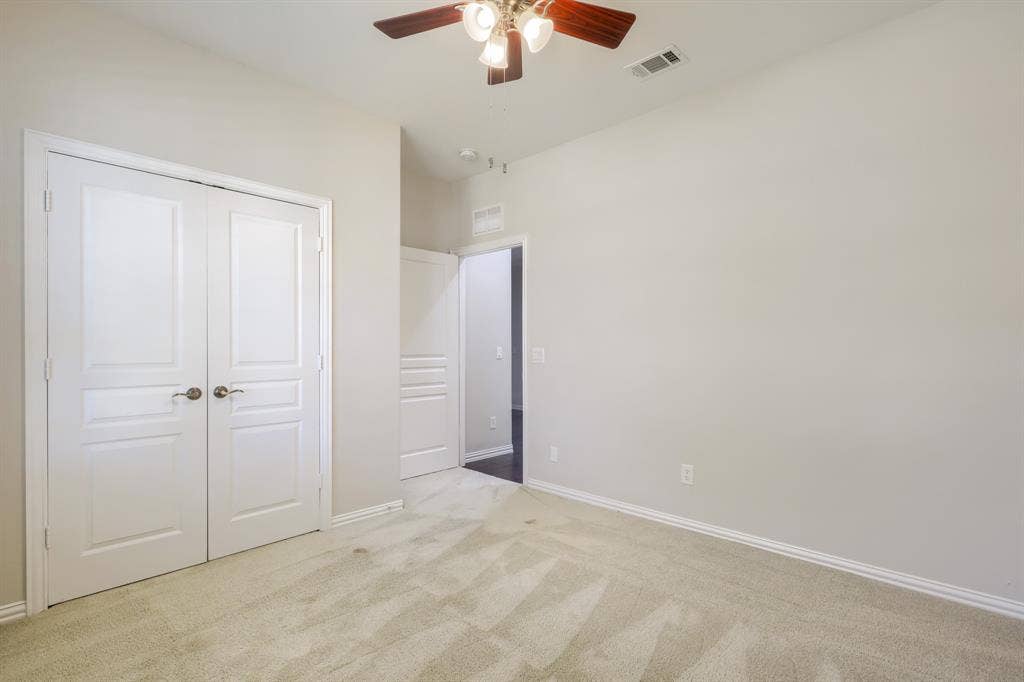 Light-toned carpeted flooring, white trim, and a ceiling fan with integrated lighting