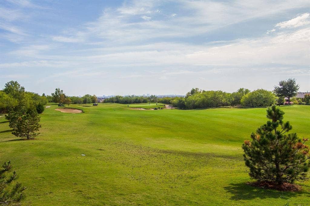 Expansive golf course setting featuring manicured greens, sand traps, and mature trees