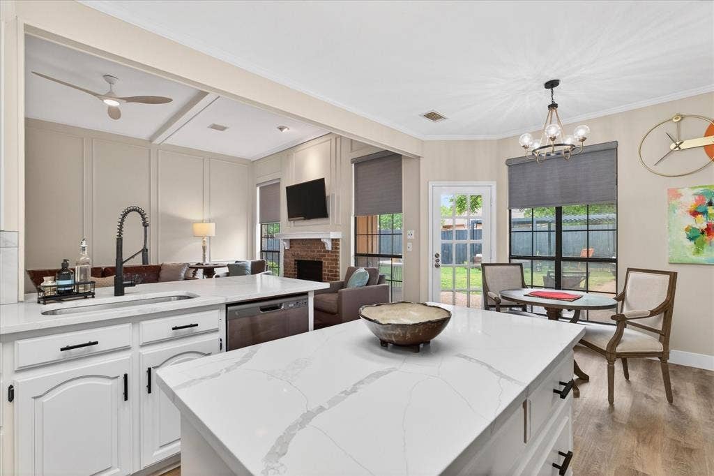 Kitchen featuring a large island with a light-toned countertop, stainless steel dishwasher, and a sink with a matte black faucet