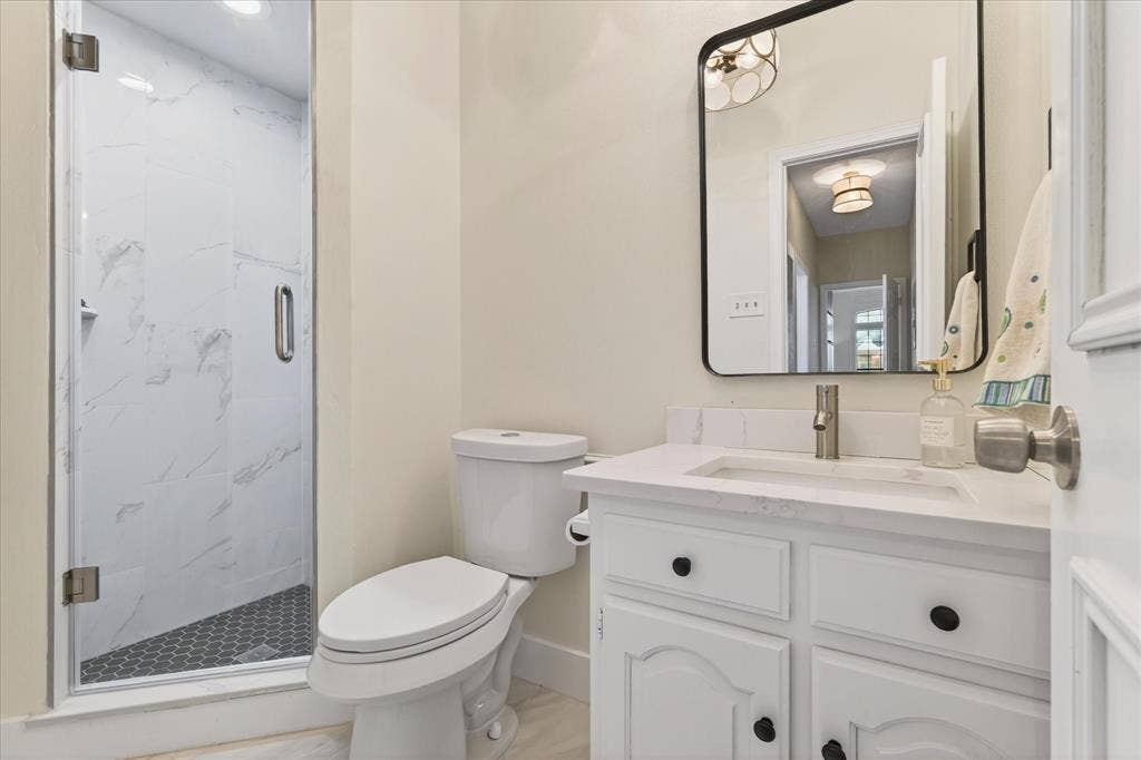 White vanity with black hardware, rectangular sink, and a framed mirror