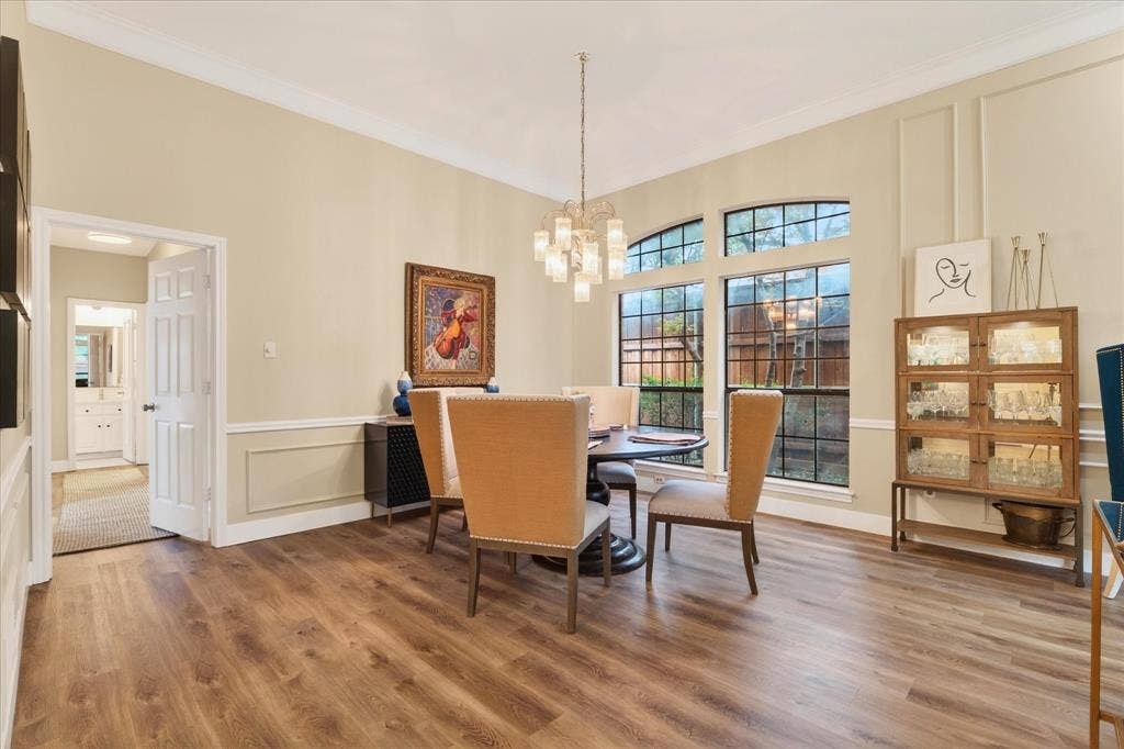 Wood-finish flooring, decorative wall molding, arched transom windows, and an elegant chandelier
