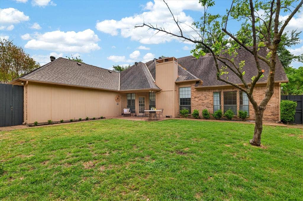 Expansive lawn with a paved patio, brick exterior, and multi-pane windows