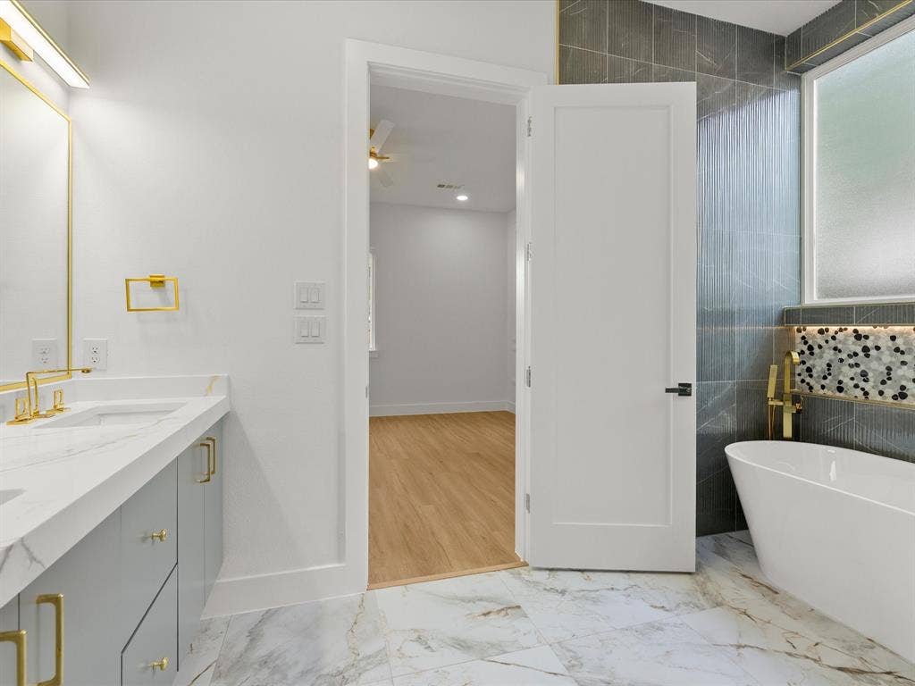 1711 Kraft Street, Dallas, TX 75212 Freestanding soaking tub with gold-tone fixtures, tiled up to the ceiling.