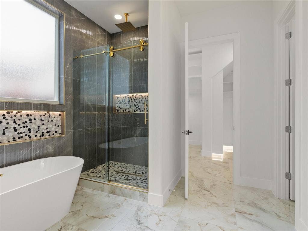 1711 Kraft Street, Dallas, TX 75212 Freestanding soaking tub, walk-in shower with glass enclosure, gold-finish shower fixtures, porcelain tile flooring.