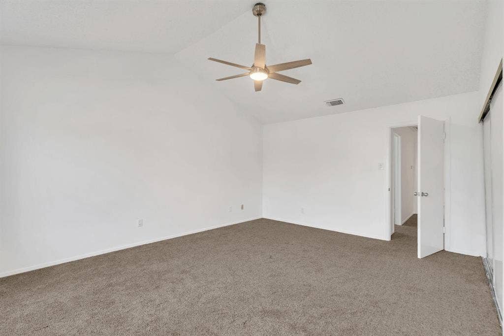 Vaulted ceiling, ceiling fan with integrated lighting, neutral carpet flooring, and white wall finishes
