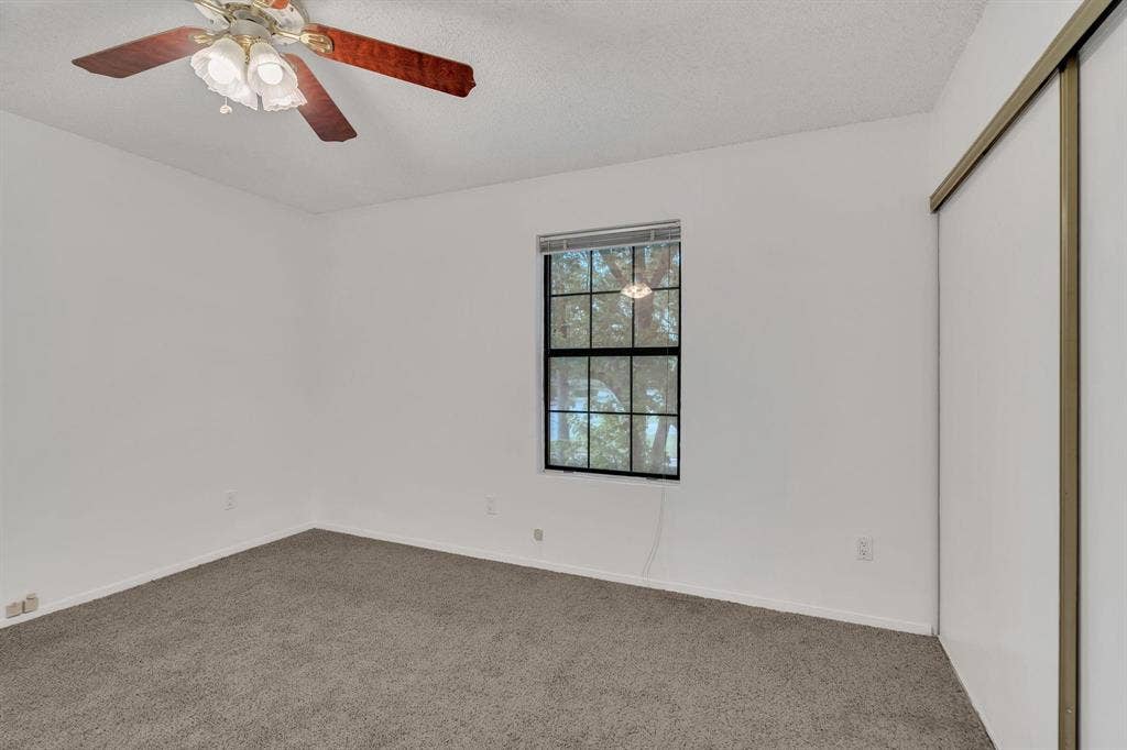 Recessed window with black gridded panes, ceiling fan with integrated lighting, textured ceiling, and sliding closet doors