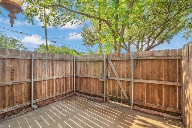 Fenced outdoor area featuring a concrete pad and a wooden gate