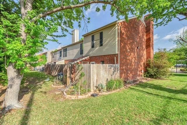 Wood privacy fence with garden beds, expansive green lawn, and mature trees