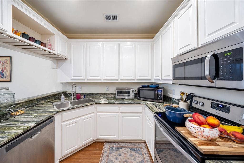 The c-shaped kitchen has stainless appliances and rich natural stone countertops. The washer and dryer is located in a utility closet in the kitchen.