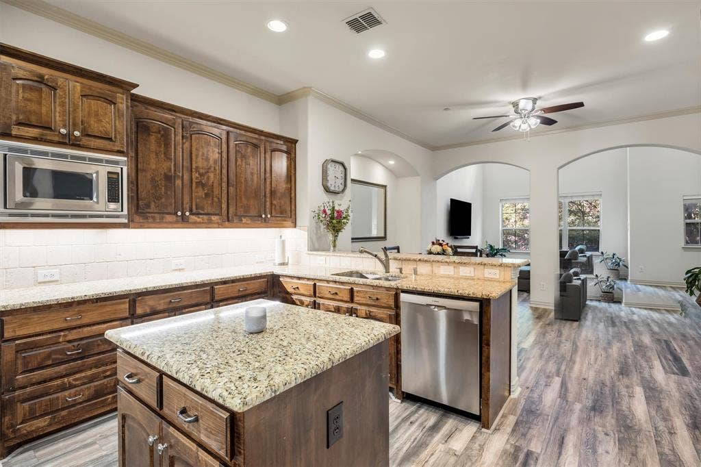 8249 Short Street, Frisco, TX 75034 Kitchen featuring wood cabinetry, granite countertops, stainless steel appliances, and a central island