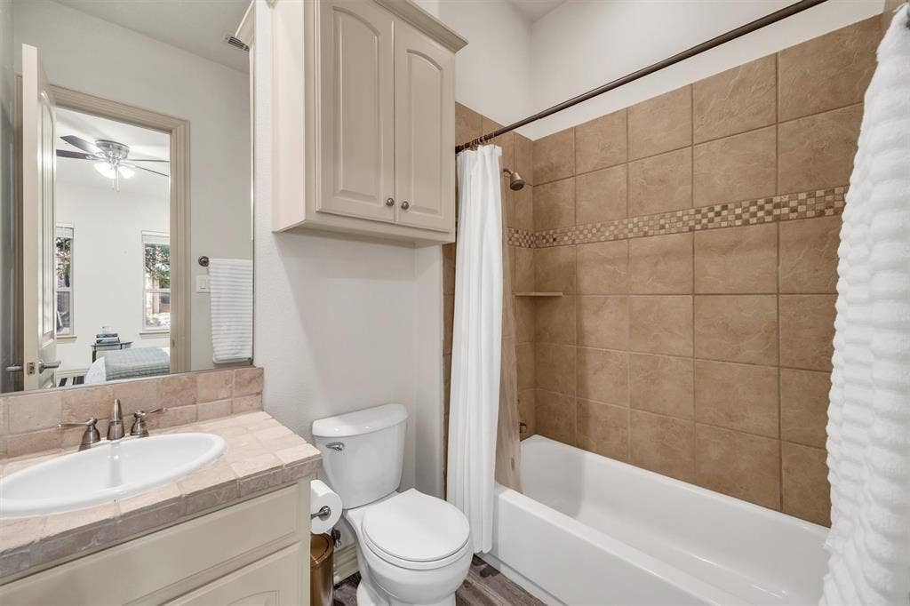 8249 Short Street, Frisco, TX 75034 Bathroom featuring a tiled shower surround with accent band, built-in shower niche, and a white tub