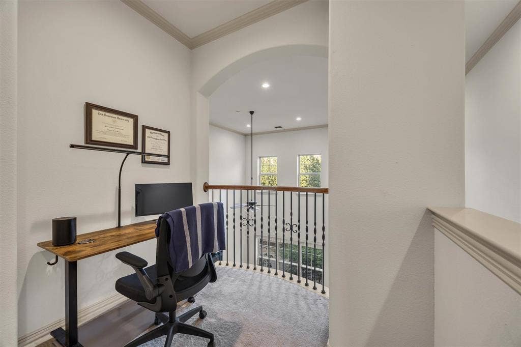 8249 Short Street, Frisco, TX 75034 Archway entry to a versatile loft space featuring wrought iron balusters, wood-finish railing, and light-toned carpeting