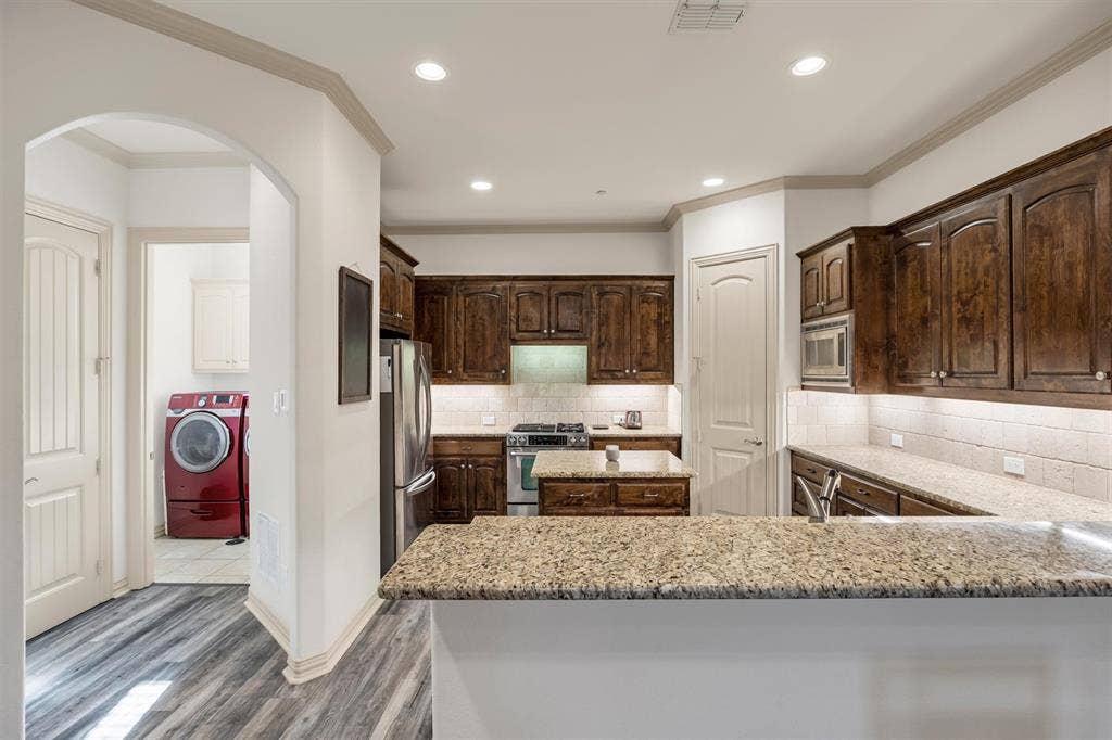 8249 Short Street, Frisco, TX 75034 Gourmet kitchen with wood-finish cabinetry, granite countertops, and stainless steel appliances