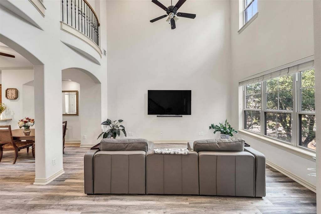 8249 Short Street, Frisco, TX 75034 Two-story living area featuring a ceiling fan, wood-finish flooring, and a bank of large windows with blinds