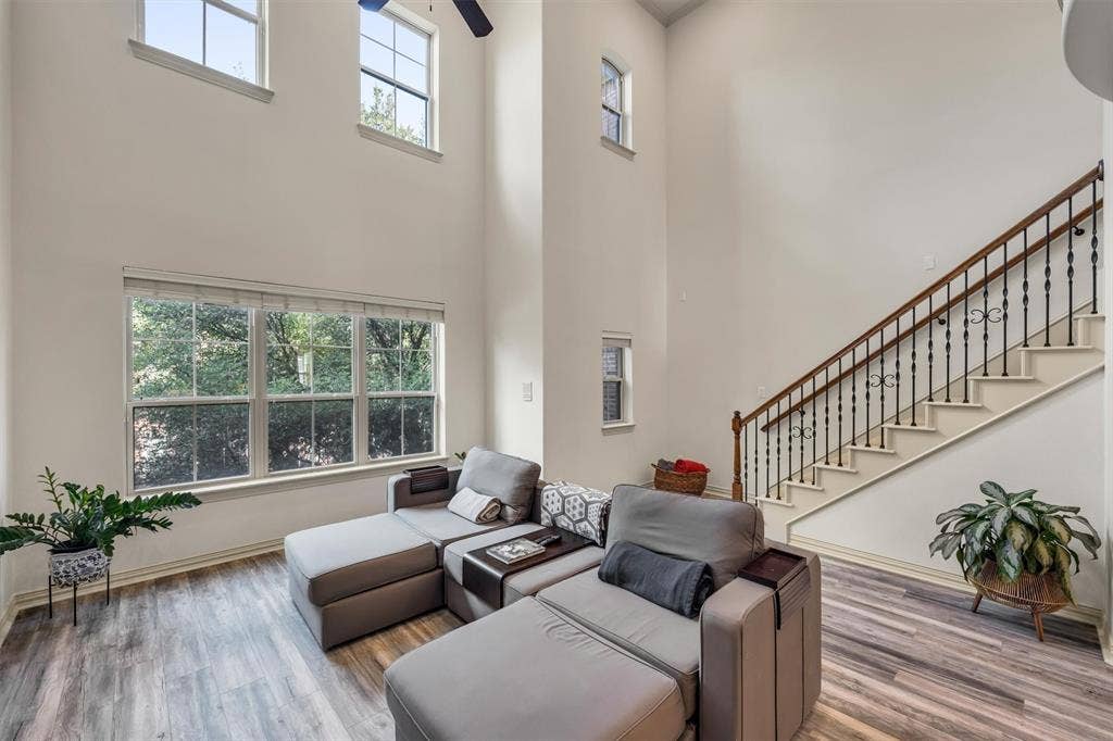 8249 Short Street, Frisco, TX 75034 High ceilings with upper windows, large picture windows, wood-finish flooring, staircase with wrought iron balusters and wood handrail, ceiling fan