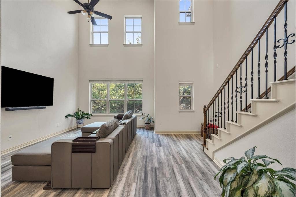 8249 Short Street, Frisco, TX 75034 High ceilings, wood-finish flooring, staircase with wrought iron balusters, multiple windows, and a ceiling fan