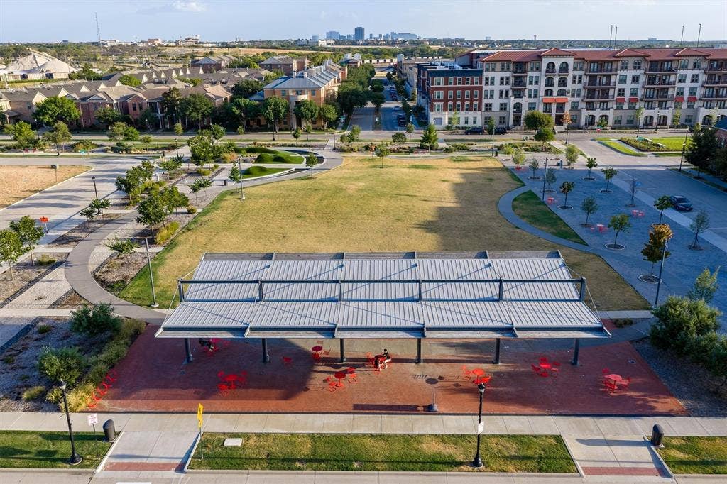 8249 Short Street, Frisco, TX 75034 Expansive park area with a large open lawn, paved walking paths, a contemporary open-air pavilion, and structured landscaping featuring trees and shrubbery