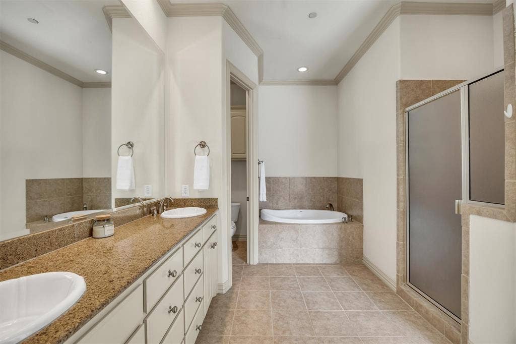 8249 Short Street, Frisco, TX 75034 Dual vanity with light-toned countertop and undermount sinks, tiled flooring, recessed lighting, built-in bathtub, and a glass-enclosed shower