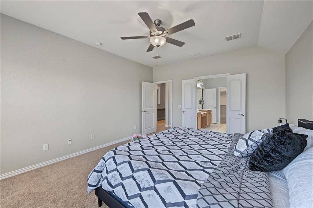 Vaulted ceiling, ceiling fan with integrated lighting, neutral wall tones, carpet flooring, and double doors