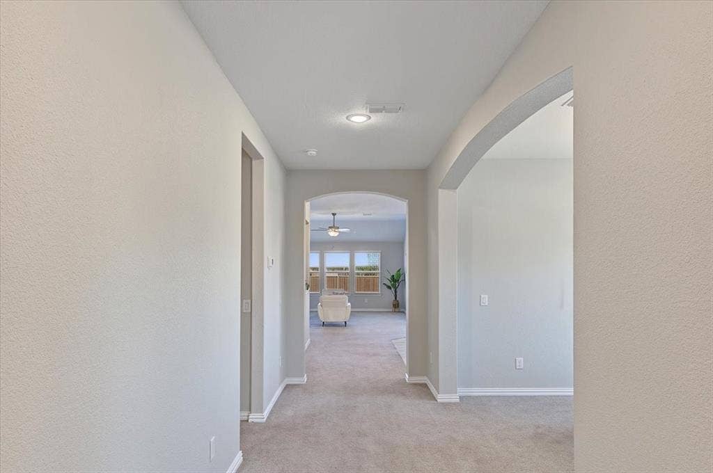 Arched doorways, recessed lighting, and light-toned walls with carpeted flooring
