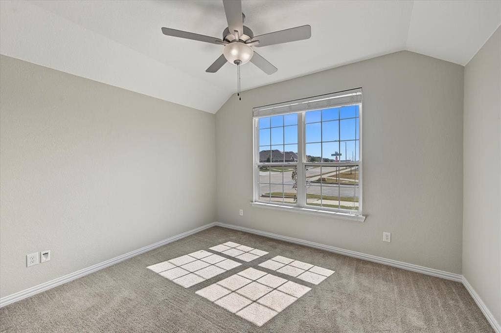 Vaulted ceiling with a ceiling fan, large window, and wall-to-wall carpeting