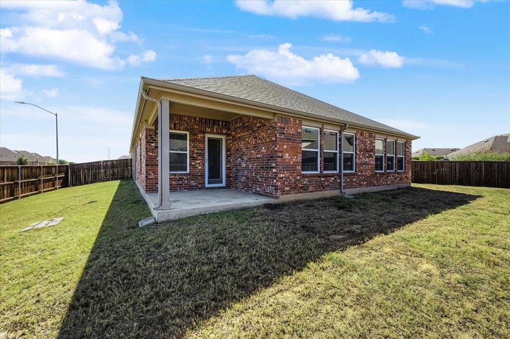 Brick exterior featuring multiple windows and a covered patio