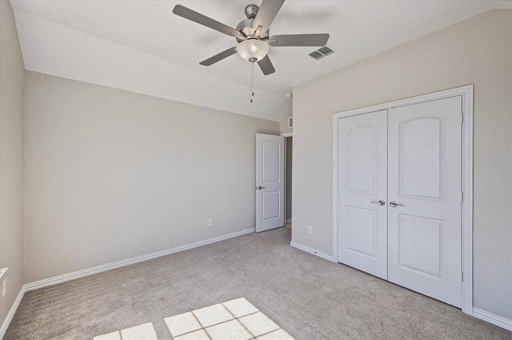 Tray ceiling with a ceiling fan, light gray wall paint, light gray carpet, and white bi-fold closet doors