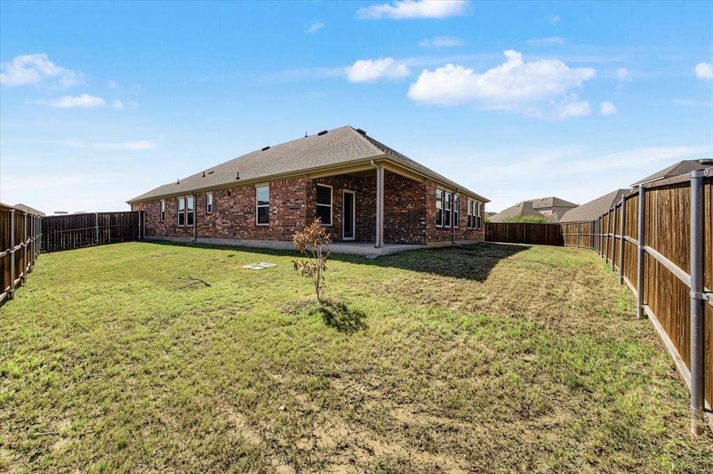 Expansive backyard featuring a brick exterior, covered patio, and wood privacy fencing