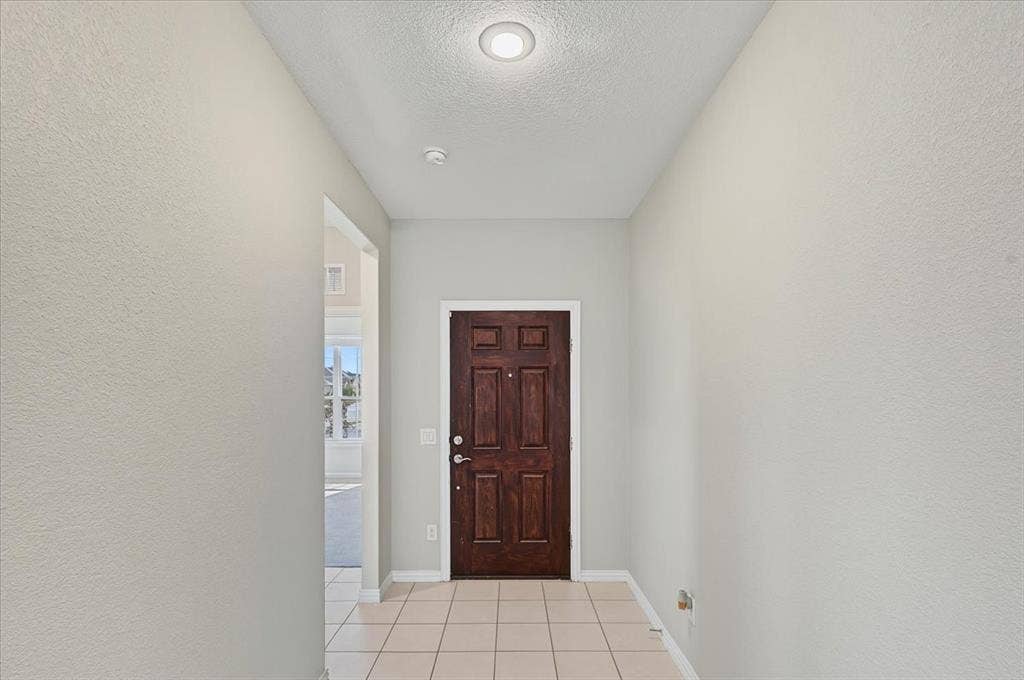 Entryway featuring a paneled wood door, recessed ceiling light, and square tile flooring