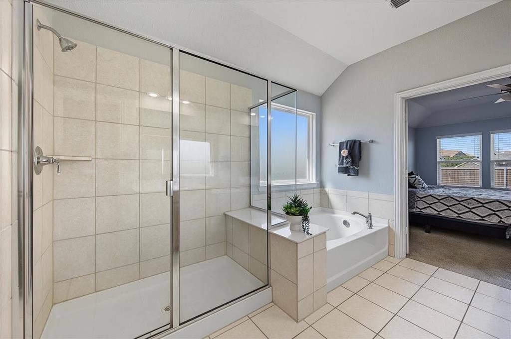 Step-in glass-enclosed shower with tile surround, built-in soaking tub, and tiled flooring