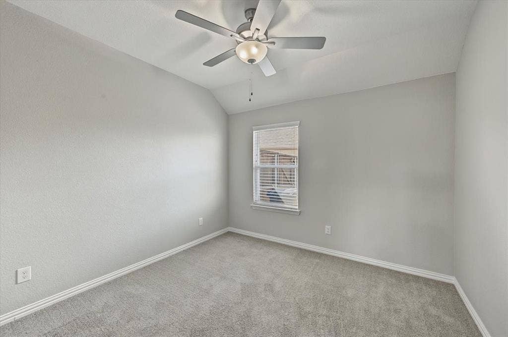 Vaulted ceiling with a ceiling fan light fixture, light gray walls, window with blinds, and gray carpet flooring