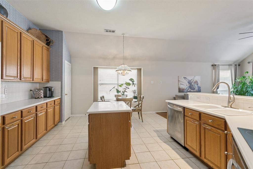 Kitchen featuring light wood cabinetry, white countertops, stainless steel appliances, and tile flooring