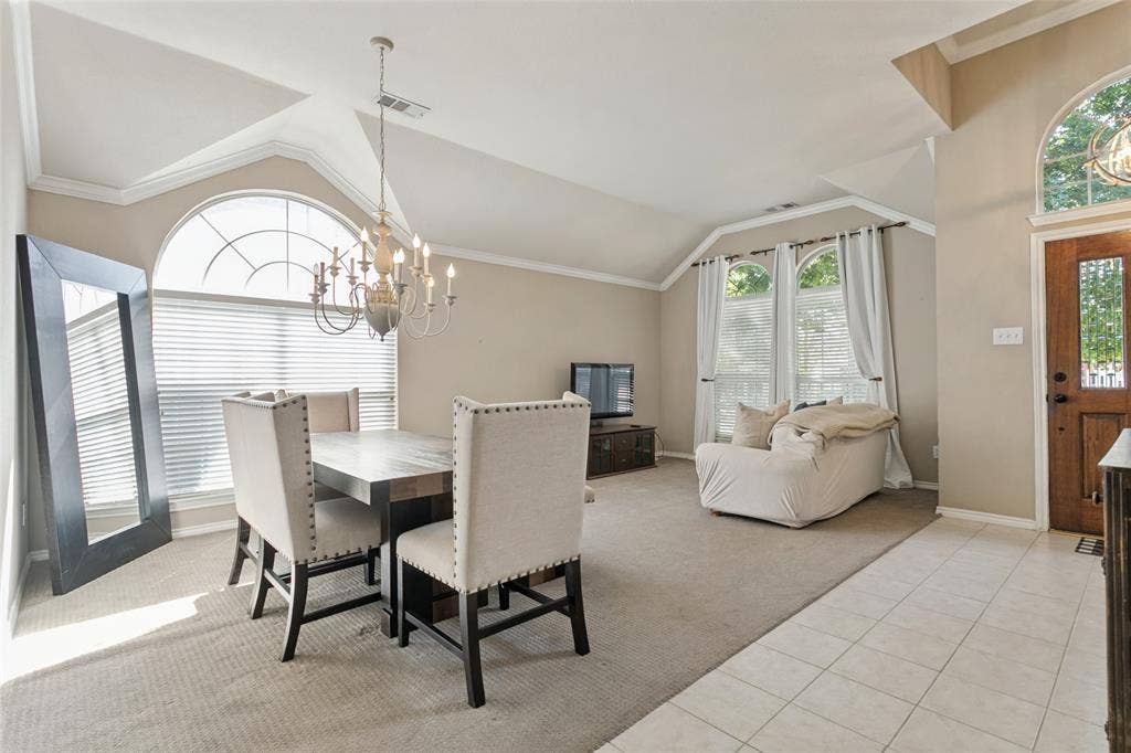 Vaulted ceilings, crown molding, arched windows, chandelier lighting, and a wood entry door