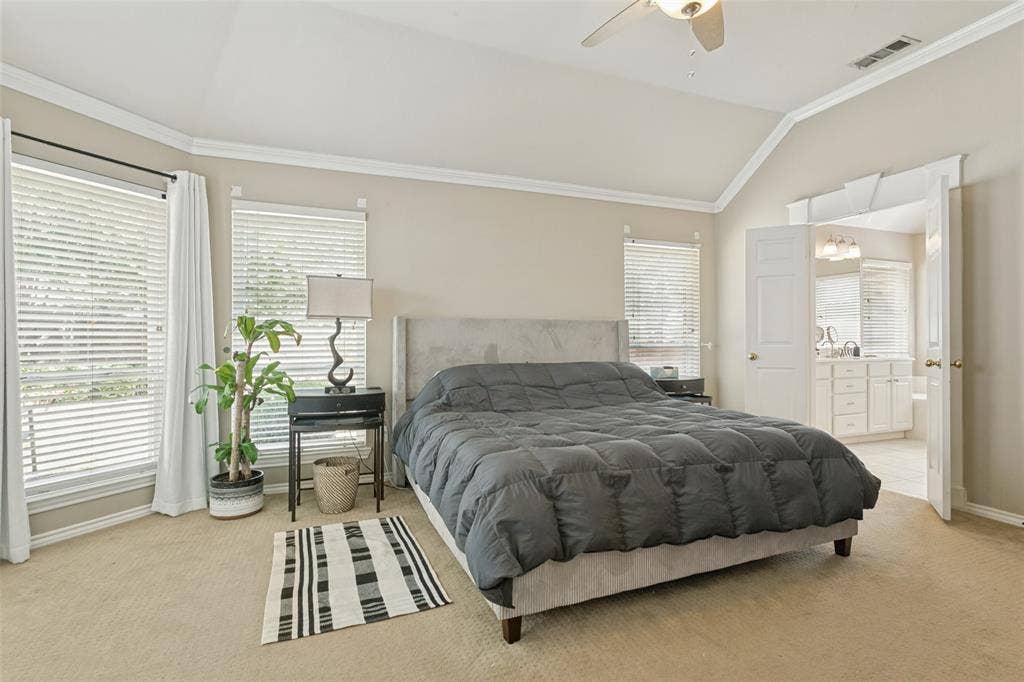Vaulted ceiling with crown molding, ceiling fan, and carpeted flooring