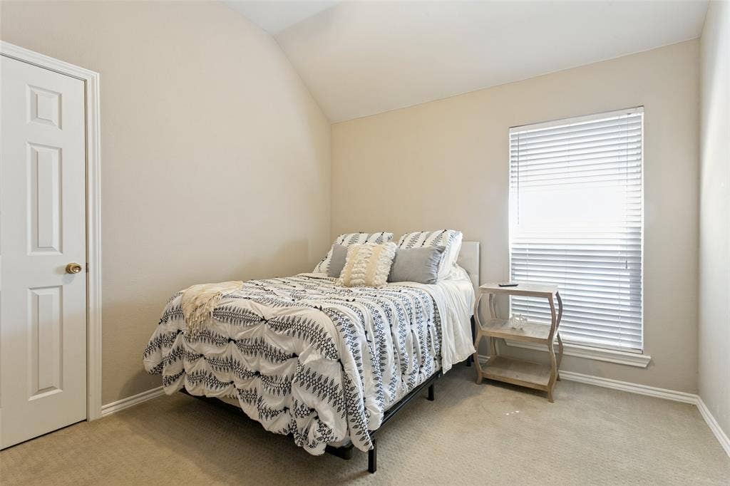 Neutral tone wall finishes, vaulted ceiling, and carpeted flooring