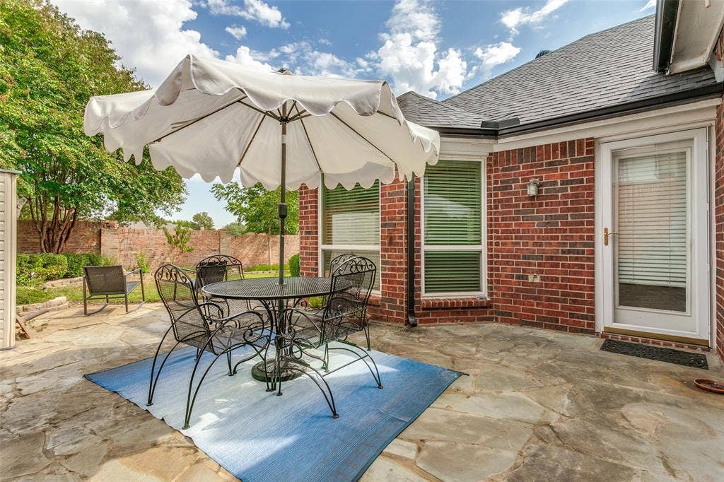 Stone patio with a brick exterior, a full-lite door, and multiple windows