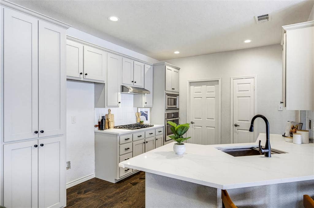 10138 Planters Row Drive, Frisco, TX 75033 Crisp cabinetry, quartz countertops, and matte black fixtures give the renovated kitchen a clean, current look, complete with a built-in water purifier.