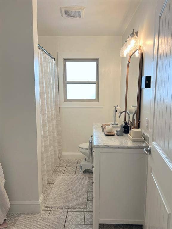 1200 Daisy Lane, Irving, TX 75061 White single vanity with a marble-finish countertop, patterned floor tiling, and a window