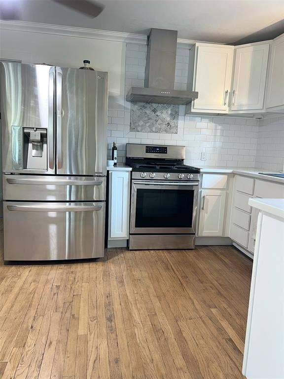 1200 Daisy Lane, Irving, TX 75061 Stainless steel refrigerator, stainless steel range with hood, white cabinetry, subway tile backsplash, and wood-finish flooring