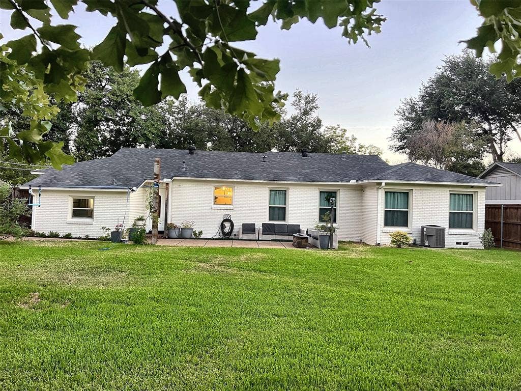 1200 Daisy Lane, Irving, TX 75061 Expansive green lawn with a white brick exterior and dark shingle roof
