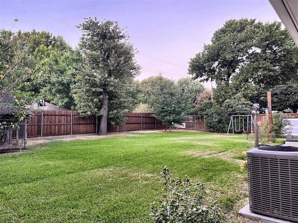 1200 Daisy Lane, Irving, TX 75061 Expansive backyard featuring a lush lawn, mature trees, and privacy fencing
