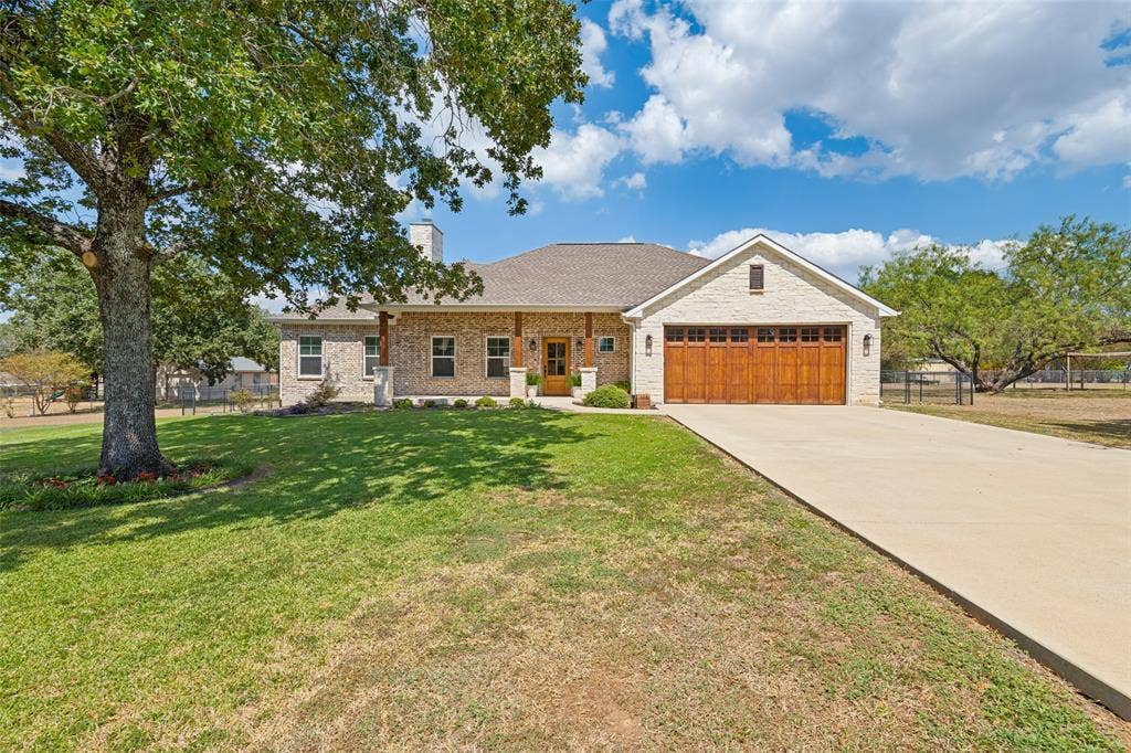 108 Rye Place, Gun Barrel City, TX 75156 Brick exterior with natural wood garage doors and front entry, covered porch, and mature landscaping